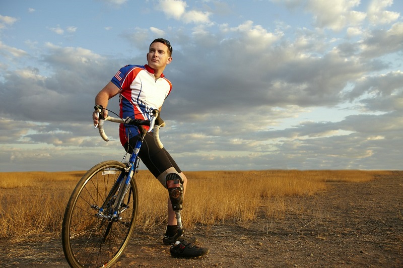 mężczyzna z protezą nogi opierający się o rower