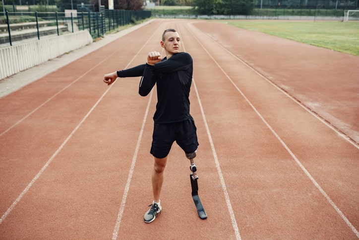 sportowiec ze sztuczną nogą rozgrzewający się na stadionie